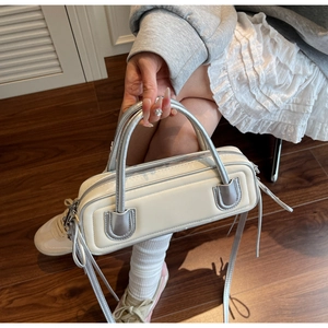 Detail view of cream shoulder bag with silver handles and unique textured stripe design