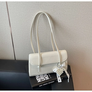 Detail view of cream white pleated shoulder bag with pearl heart charm and ribbon