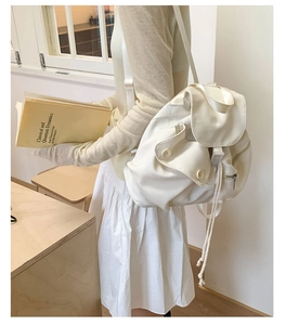 Detail of minimalist cream canvas backpack featuring flap top and drawstring closure