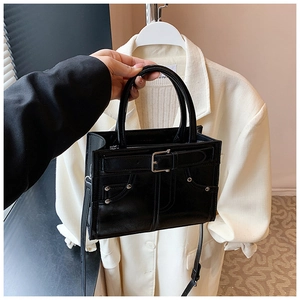 Détail du sac à main en cuir noir mat avec boucle métallique et rivets argentés