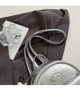 Detail of silver metallic mini backpack with pleated texture and adjustable thin straps