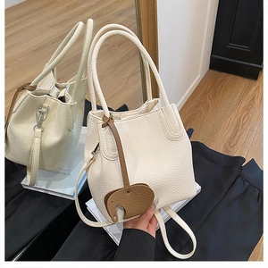 Détails du sac seau blanc crème avec texture grainée et charm en forme d'éléphant