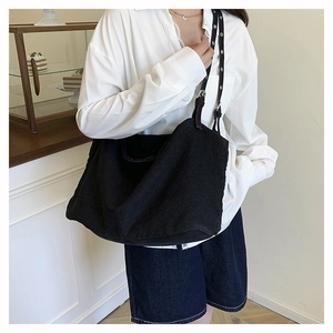 Detail of adjustable metal buckle on wide canvas strap of black crescent tote bag