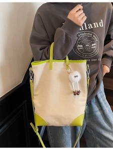 Minimalist canvas tote bag with green leather trim and cute plush charm detail