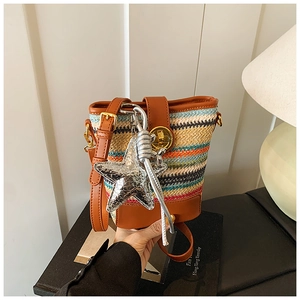 Close-up of multicolor woven straw bucket bag with silver star charm and leather trim