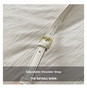 Gros plan sur la bandoulière réglable en cuir blanc avec boucle dorée et coutures fines