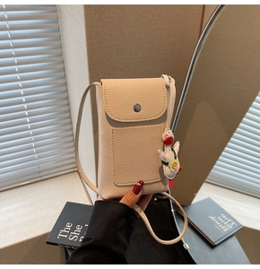 Detail of beige lychee leather crossbody phone bag with cute duck charm and card slot