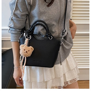 Black litchi grain bucket bag with teddy charm and ribbon shown on a model