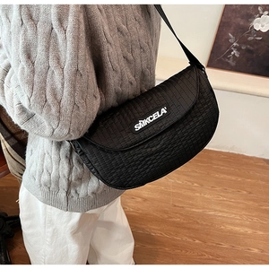 Detail of black quilted nylon saddle bag featuring an adjustable strap and white brand logo