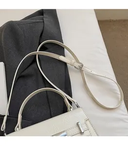 Detail view of cream crossbody bag with silver hardware and adjustable leather strap