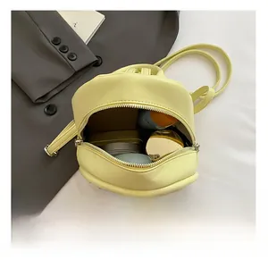 Detail showing internal capacity of yellow mini quilted backpack with makeup items
