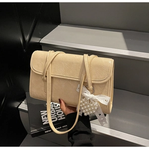 Detail of cream beige faux leather shoulder bag with lace bow pearl heart charm decoration