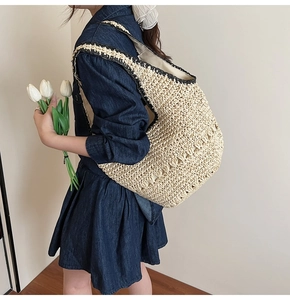 Detail shot of hollow weave straw shoulder bag with black trim and spacious interior