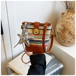Detail of colorful woven bucket bag with brown leather trim and star pendant