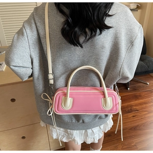 Borsa baguette bicolore rosa e bianca con nappine mostrata sulla schiena della modella