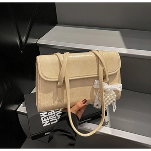 Detail of light beige pleated leather shoulder bag with lace bow and pearl charm