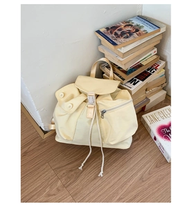 Detailed close-up of a light beige canvas backpack with drawstring closure and buckle