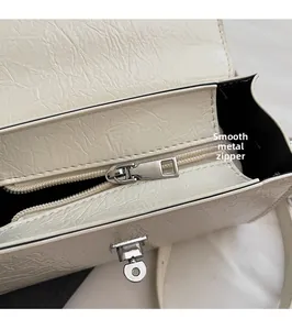 Close-up of smooth hardware zipper and metal lock on off-white textured leather bag