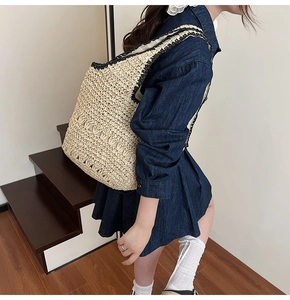 Detail view of woven straw tote bag with black trim and hollow-out knitting pattern