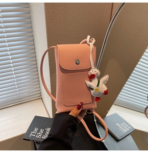 Close-up of pink litchi leather phone bag with a cute white duck charm and snap closure