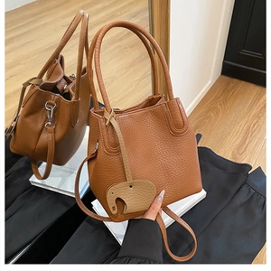 Détail d'un sac seau marron en cuir grainé avec un pendentif en forme d'éléphant
