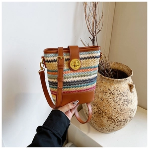 Detailed shot of multi-colored woven bucket bag with leather trim and gold twist lock