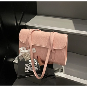 Detail of pink pleated leather shoulder bag with pearl bow charm held by a model