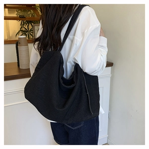 Close-up of minimalist black canvas tote bag showing textured fabric and wide shoulder strap
