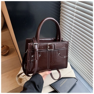 Détail d'un sac à main vintage marron foncé avec texture cuir huilé et boucle décor
