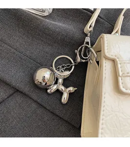 Close-up of a silver balloon dog charm with round metal pendant on a white leather bag
