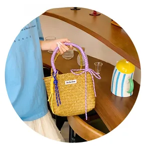 Detailed close-up of handmade straw bucket bag with purple handle and woven texture