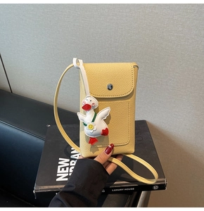 Detail of yellow lychee textured phone bag with cute duck charm and metal buckle