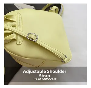 Detail view of adjustable leather shoulder strap and metallic buckle on yellow bag