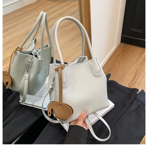 Détail du sac seau en cuir grainé blanc avec un pendentif éléphant marron mignon