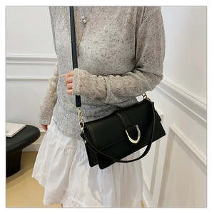 Détail d'un sac à bandoulière en cuir noir avec boucle dorée et sangle amovible réglable