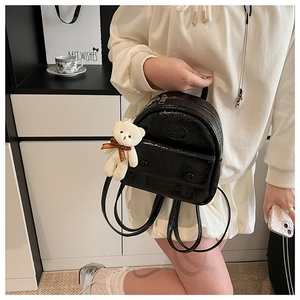 Detail of vintage mini backpack in glossy black pleated leather with plush bear charm
