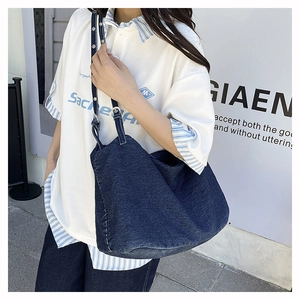 Detail shot of a large navy blue washed denim tote bag worn on shoulder for daily style