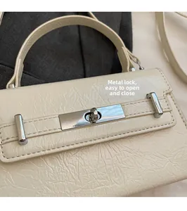 Detail of silver turn-lock closure on a creamy white pleated texture handbag