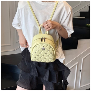 Detail of yellow quilted mini backpack featuring star charm and silver rivet accents