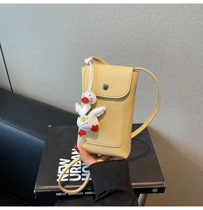 Detail of yellow lychee texture leather crossbody phone bag with cute duck charm