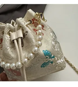 Detail of embroidered silk bucket bag with pearl handle and traditional carp motifs