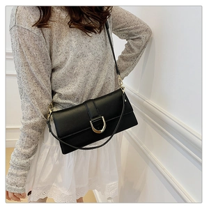 Détail d'un sac à bandoulière en cuir noir avec boucle dorée en forme de D