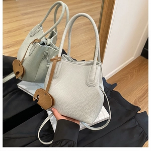 Détail du grain de litchi et de la breloque éléphant sur le sac seau gris élégant