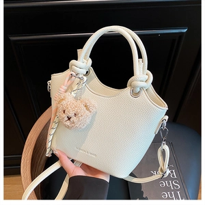 Detail of lychee pattern leather bucket bag with knot handle and bear charm pendant