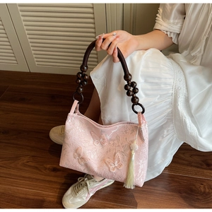 Détail du sac cabas en jacquard rose avec broderie papillon et poignée en perles de bois