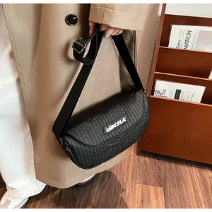 Close-up of black quilted saddle bag with adjustable wide strap in a lifestyle setting