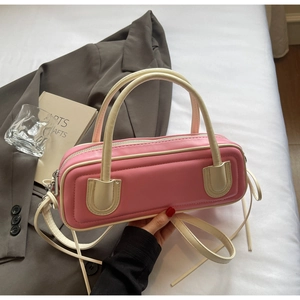 Detailed view of pink baguette handbag featuring contrast trim and top metal zipper detail