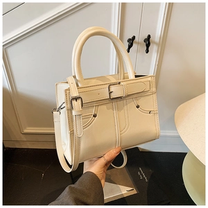 Détail d'un sac à main beige en cuir PU avec boucle argentée et bandoulière réglable