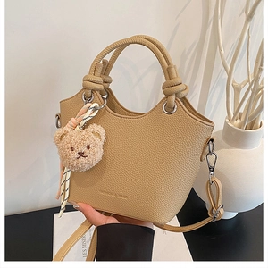 Close-up of khaki bucket bag with lychee texture and cute bear pendant detail