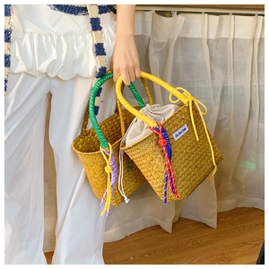 Detail of hand-woven straw bucket bag with contrasting cord handles and inner drawstring